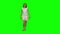 Young woman with brown hair and smooth haircut is calmly walking on green screen. Chroma key, 4k shot. Front view.