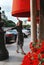 Young woman in a brown long dress and heels on a street in the city, flowers on a flower bed, buildings, Saint Petersburg