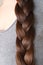 Young woman, brunette, braids her brown long beautiful hair in thick braid, concept of hygiene, hair care, traditions