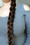 Young woman, brunette, braids her long beautiful hair in a thick braid, concept of hygiene, hair care, traditions