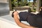 Young woman, brunette, slender, dressed in black and wearing sunglasses, lying on a bench receiving the sun\'s rays relaxed.