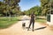 Young woman, brunette, slender, dressed in black and wearing sunglasses, walking her dog in a park. Concept beauty, fashion,