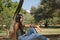 Young woman, brunette, slender, dressed in green T-shirt and jeans, sitting on a stone bench, alone, sad, serious. Concept