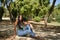 Young woman, brunette, slender, dressed in green T-shirt and jeans, sitting on a stone bench, alone, sad, serious. Concept