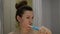 Young woman brushes her teeth with an electric toothbrush