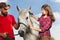 Young woman brushing beautiful white horse