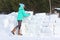 Young woman builds snow castle wall of snow blocks. Winter vacation. Winter and new year holidays