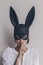 Young woman in bunny mask showing quiet sign