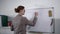 Young woman business woman or teacher writes homework for students on whiteboard with erasable marker