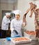 Young woman butcher holding meat sausages