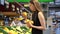 Young woman buying apples in fruit and vegetable department of store