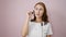 Young woman call center agent speaking over isolated pink background