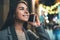 Young woman calling mobile phone on background bokeh light in night europe city. Smiling girl using smartphone technology