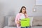 Young woman calling roof repair service while collecting leaking water from ceiling