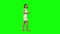 Young woman is calmly walking and texting message vie her mobile phone on green screen. Profile view.