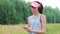 Young woman in cap listens to music and sings at summer outdoor