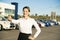 Young woman car rental in front of garage with cars on the background