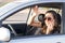 A young woman in the car talks on the smart phone and drives
