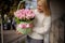 Young woman carefully holds basket with pink ribbon and pink flowers inside