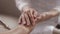 Young woman caregiver holding hand of old man, closeup view