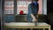 Young woman carpenter removes wood dust from countertop using vacuum cleaner.