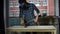 Young woman carpenter removes wood dust from countertop using vacuum cleaner.