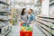 Young woman with cart full of goods in supermarket