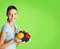 Young woman in casual clothing, with plate of fruits. green background. copy space