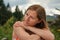 Young woman casual portrait - leaning on her palm and shoulder looking to side, closeup detail, blurred trees background