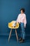 Young woman in casuals looking at her white dog on yellow chair