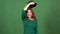 Young woman celebrating saint patrick`s day on green wall throwing hat