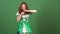 Young woman celebrating saint patrick`s day on green wall wearing traditional dress holding pot with money