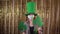 young woman celebrating st patrick\'s day, dressed in a leprechaun costume with a protective mask on her face, dancing