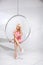 Young woman in a chair on a white background. Geometry. Blonde in a pink dress in a plastic round chair