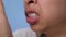 Young woman chewing gum and covering mouth to check breath with her hand on blue background.