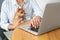 Young woman with chihuahua working on laptop at table, closeup. Home office concept