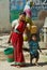 Young woman with a child carries plastic bucket with water at the street in Orchha, India.