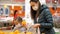 Young woman with child girl in medical masks buys a oranges at supermarket