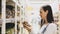 Young woman is chooses canned mushrooms in glass jar at supermarket.