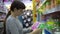 A young woman chooses a plastic lunch box in the supermarket.