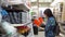 A young woman chooses a small orange container in a building supermarket.