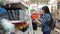 A young woman chooses a small orange container in a building supermarket.