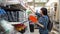 A young woman chooses a small orange container in a building supermarket.