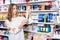 Young woman choosing hair fixation spray in cosmetics store