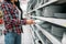 Young woman choosing plates in supermarket