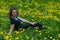 Young woman in city park during dandelion flowering. Yellow cheerful lightning concept. Symbol of happiness and freedom