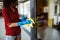 Young woman cleaning the door handle with a rag wearing blue rubber gloves. Business office disinfection during coronavirus