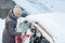 Young woman cleaning her car from snow and frost