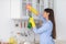 Young woman cleaning shelfs at home at kitchen