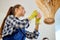 Young woman cleaning wooden chandelier with rag